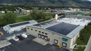 Aerial view of Artisun Solar panels on Storm Products building, mountains in background.