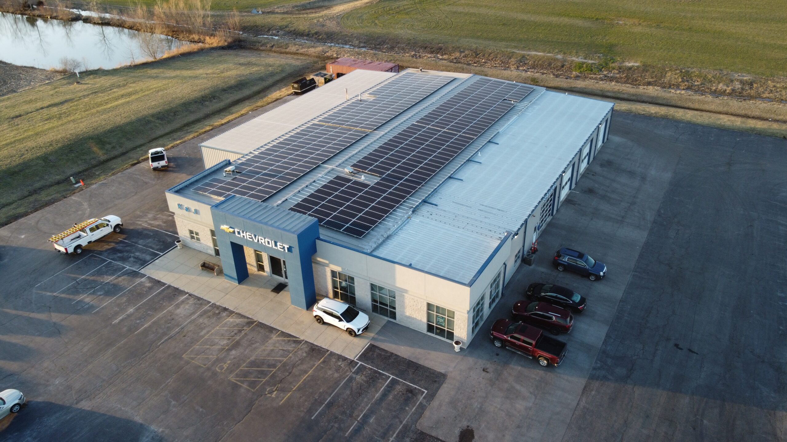Cinematic aerial image of the K&J Chevrolet building and its newly installed solar array that is projected to save $15,911 in its first year.