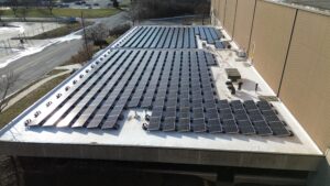 Close-up aerial view of the solar panels and mounting hardware installed on Preston Refrigeration's flat rooftop.