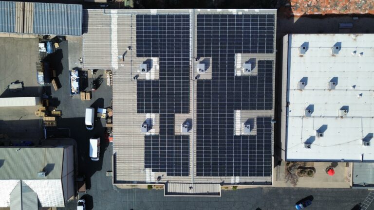 Straight top-down aerial photograph of the Design to Print facility roof, highlighting the symmetric grid engineering of the 250 kW (DC) solar system.