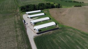 Wide aerial view of the four-barn Judson Vos farm and ground-mount solar array with a 2.1-year payback in Sully, IA.