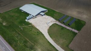 Aerial view of Tass Pork barn, feed silos, and 56.6 kW ground-mount solar array in Ashton, IA.