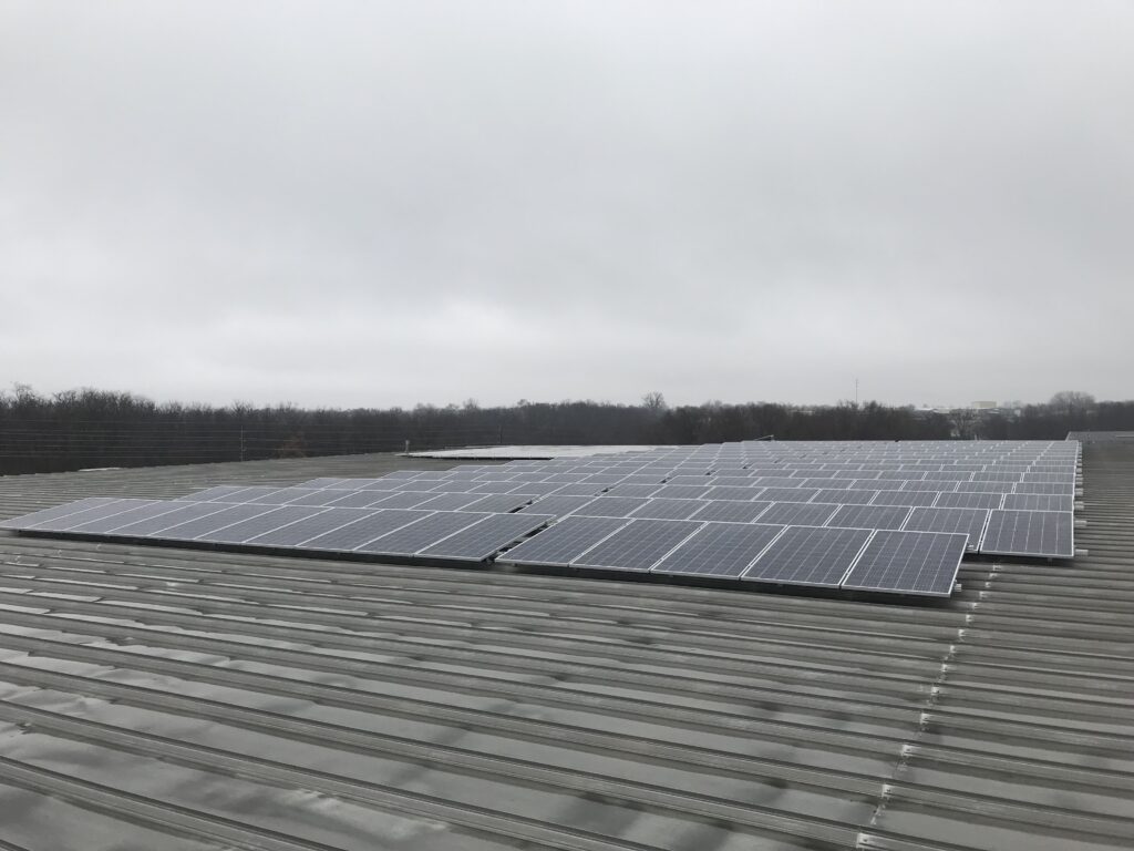 A 446-panel rooftop solar array on a corrugated metal industrial roof at US Toy's Grandview, MO facility, representing the 149.41 kW (DC) system installed by Artisun Solar in 2018.