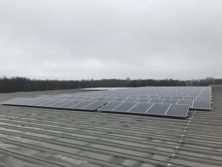 A 446-panel rooftop solar array on a corrugated metal industrial roof at US Toy's Grandview, MO facility, representing the 149.41 kW (DC) system installed by Artisun Solar in 2018.