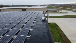 Aerial drone view of Ultimate Air's Scott City, MO rooftop solar installation, showing 210 panels mounted on a flat commercial roof with inverter equipment and electrical conduit visible.