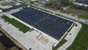 High-angle aerial drone view of the Jenne Distributors commercial facility in Avon, Ohio, showing the extensive 2,140-panel rooftop solar panel installation.