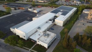 Aerial view of PFlow Industries' Milwaukee solar installation showing the rooftop array and facility branding, with the system designed to offset 97.13% of total facility electricity consumption.