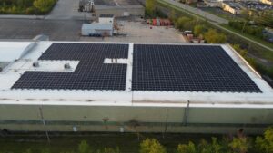 Aerial view of PFlow Industries' Milwaukee rooftop solar system showing the 1,220-panel array engineered around existing HVAC infrastructure on the flat commercial roof.