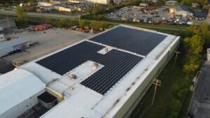 Wide aerial photograph of Artisun Solar's rooftop installation at PFlow Industries' Milwaukee facility, showing the 499.8 kW DC array configured across the flat white roof membrane.