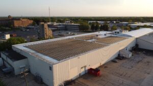 Oblique aerial drone view of PFlow Industries' Milwaukee solar installation, showing the 499.8 kW DC rooftop system against the surrounding industrial district.