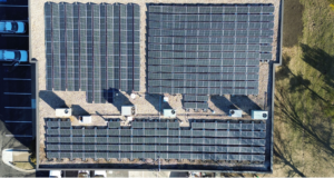 Directly overhead aerial view of three commercial solar panel array layouts on a flat roof.